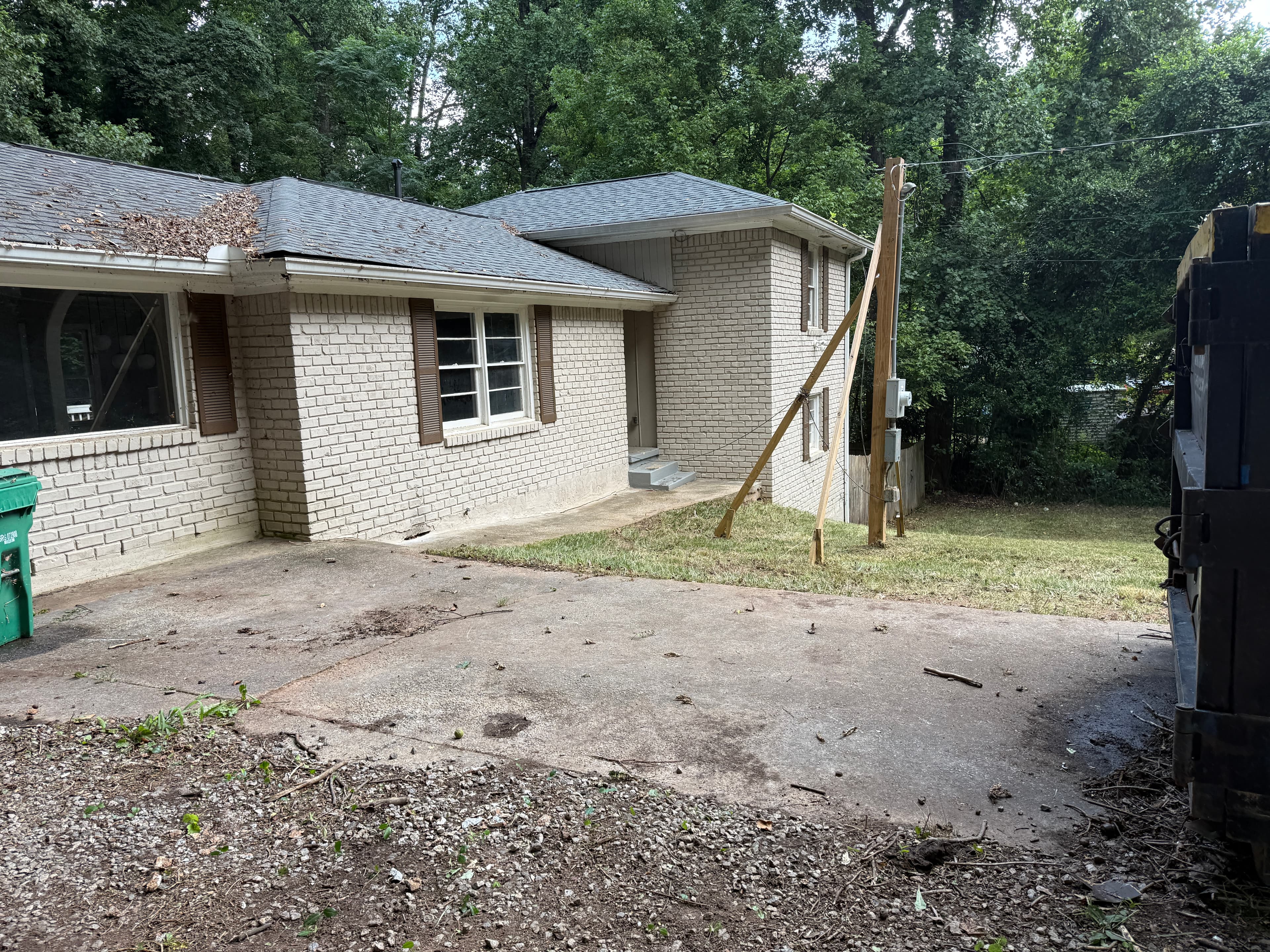 Exterior of the house with a temporary power pole and debris cleared from the driveway, July 2025
