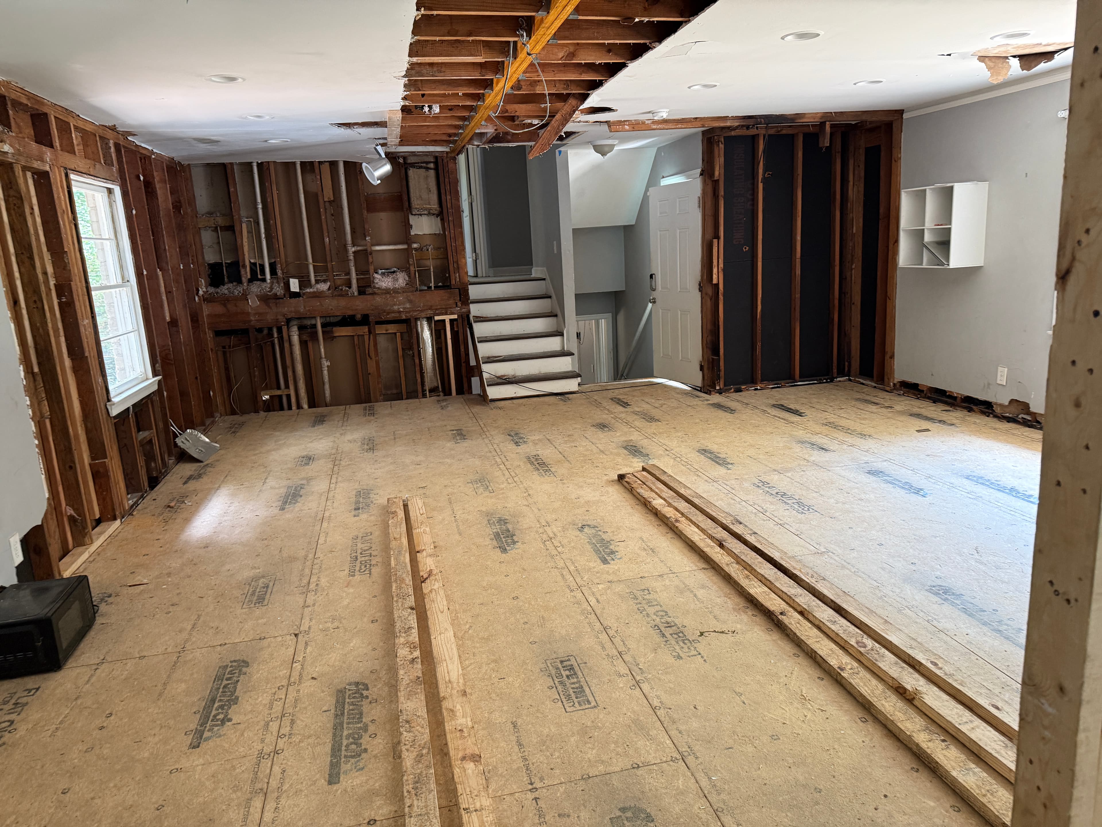 Interior of the house stripped completely to bare studs and subfloor during demolition, July 2025